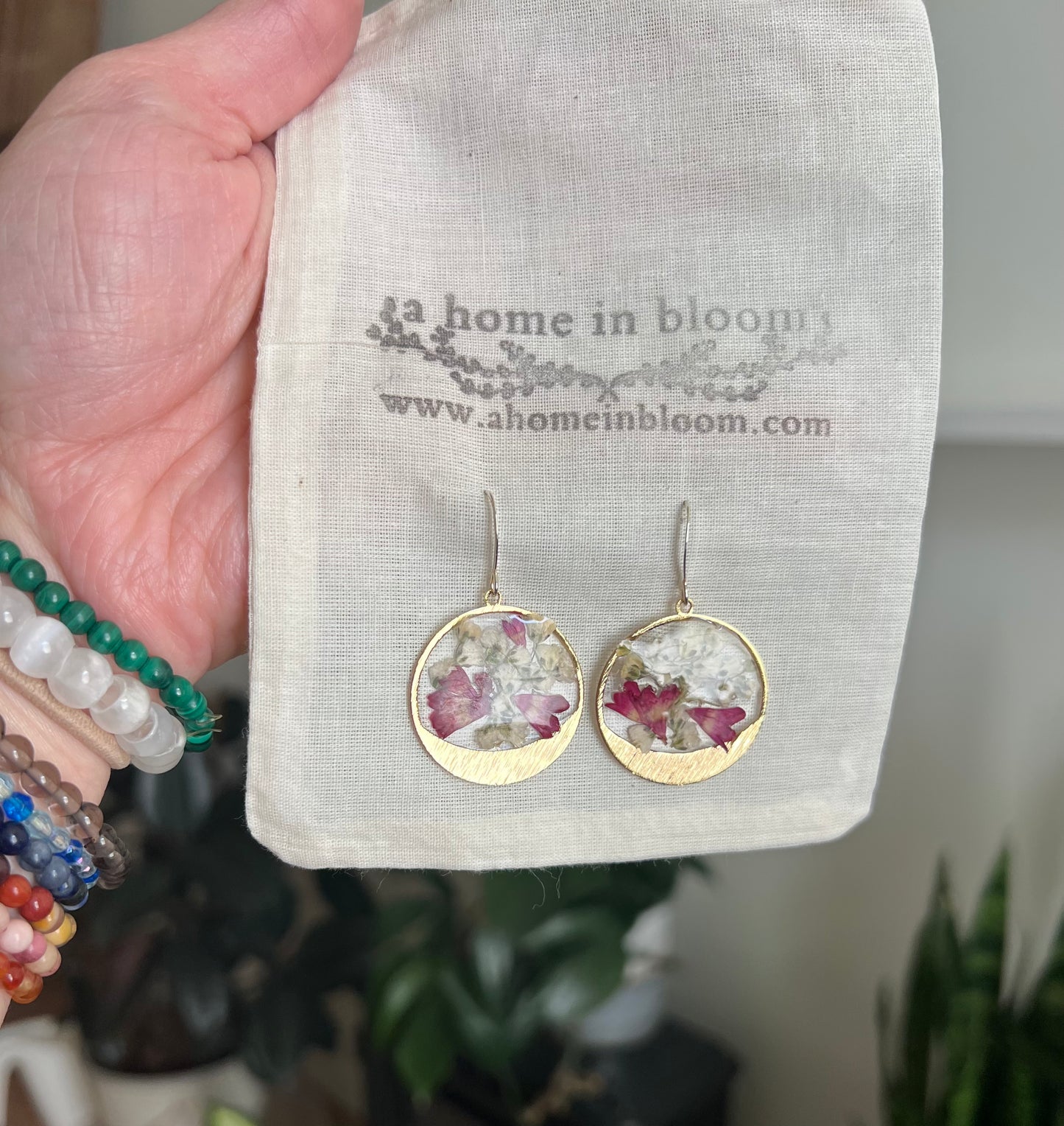 A pair of earrings featuring pressed florals encased in clear resin, set within gold hoop frames. The earrings display delicate flowers, adding a natural and elegant touch to the design.